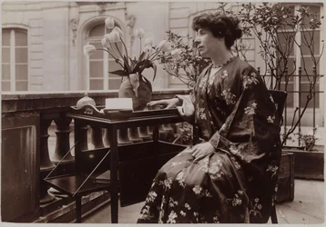 Marcelle Tinayre zittend, een boek op een tafel voor haar